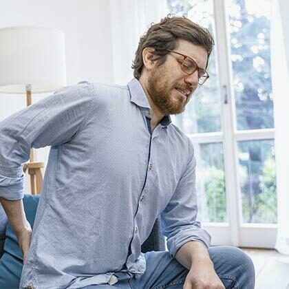 Man in pain sitting with one hand on his lower back