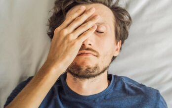 man covering eye and forehead with hand