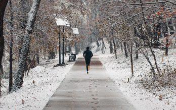 Person runs on a snow covered walking trail in the winter