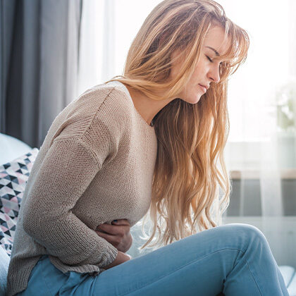 A woman experiencing IBS issues holds her stomach