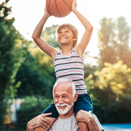 Older man with a boy on his shoulders holding a basketball