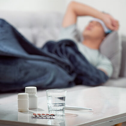 photo of pills with a sick patient in the background
