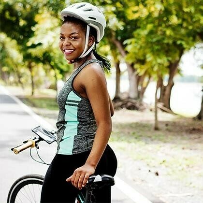 Woman stopped on a trail with her bicycle.