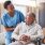 Nurse speaks to an elderly man in his wheelchair