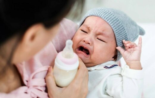 Mom tries to feed fussing baby