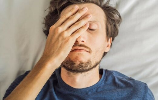 man covering eye and forehead with hand
