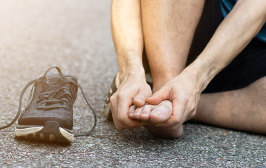 Man holding his foot in pain with his running shoe next to him