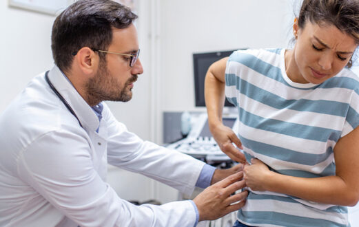 A healthcare provider probes a female patient's abdomen to check for kidney issues.