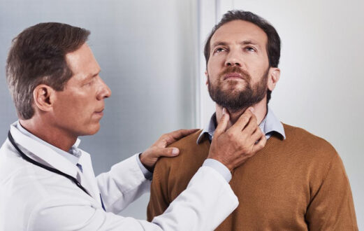 A physician palpates a man’s neck during a thyroid examination.