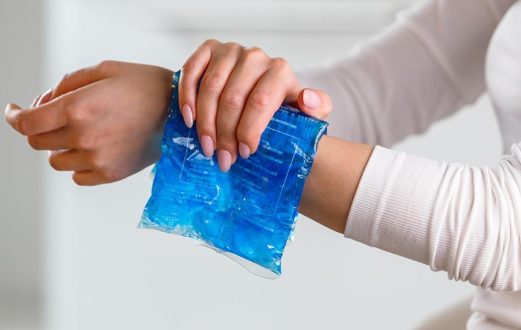 Person holding a cold gel pack against their wrist for pain relief.