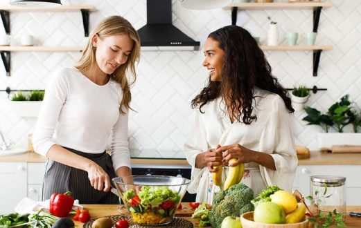 Two Young women prep fruits and vegetables for a meal