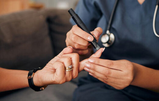 Nurse checks patients blood sugar with finger prick test