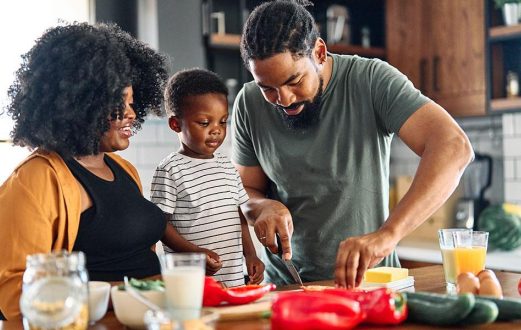 A mom, dad and young son prepare a meal together in the kitchen
