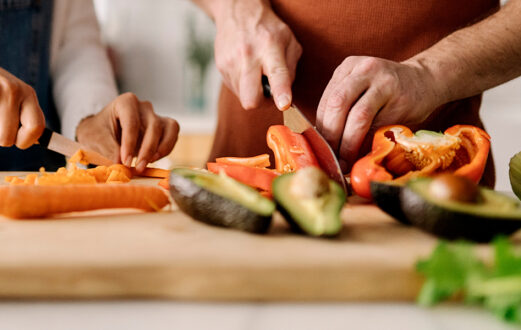 Two people chopping vegetables on a cutting board