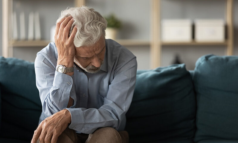 Elderly man on couch with headache