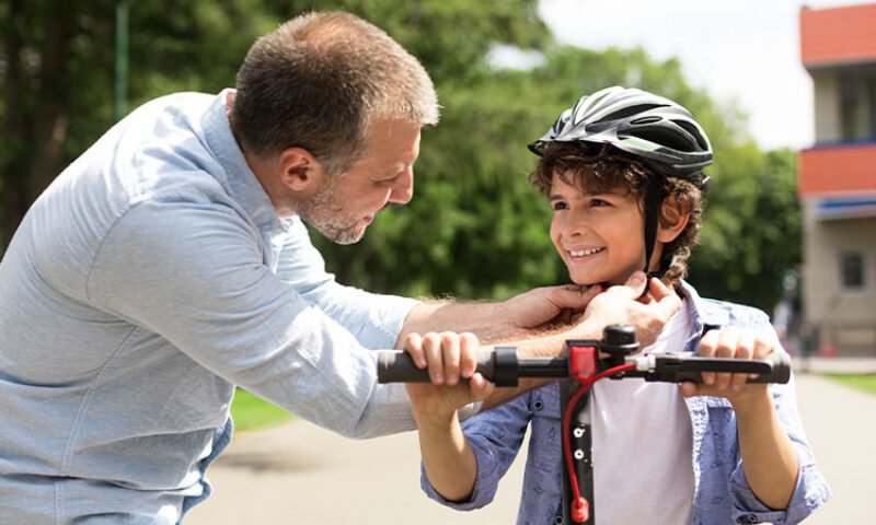 photo of dad putting bike helmet on child