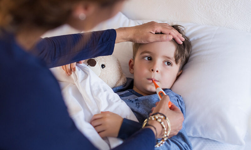 photo of little boy sick checking his temperature