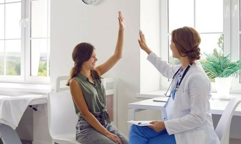 A health provider gives her female patient a high five.