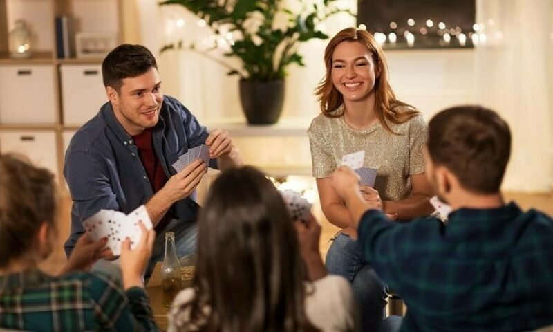 A couple enjoys life and focuses on mental health by inviting friends over for a card game.