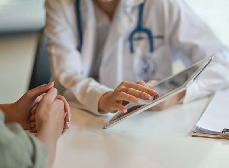 close up of doctor's hands on an iPad with a patient