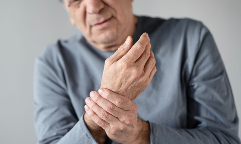 older man grabbing his right wrist in pain