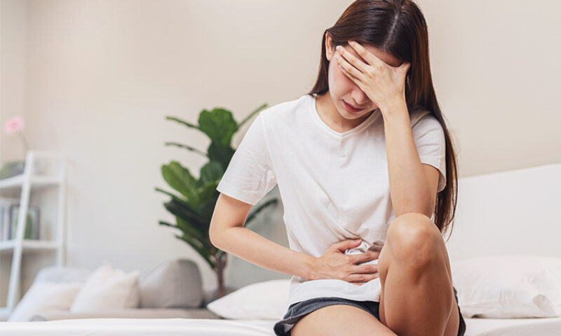 woman holding her head and her stomach in pain