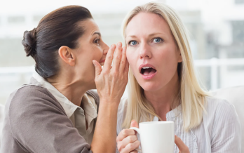 girl telling another girl a secret with a shocked face