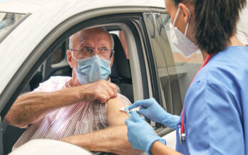 Man with mask getting a flu shot while in his car