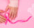 Hands folding a pink ribbon