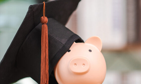 graduation cap leaning against a pink piggy bank