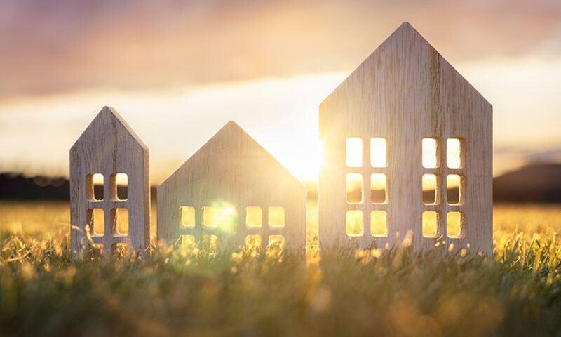 Wooden cut-outs of houses with the sun setting behind