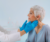 A doctor wearing a white lab coat and blue gloves checks the throat glands of an elderly patient.