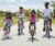 Family of mother, father and two young girls ride bikes down a neighborhood street