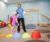 Physical Therapist helps child walk over colored stepping forms