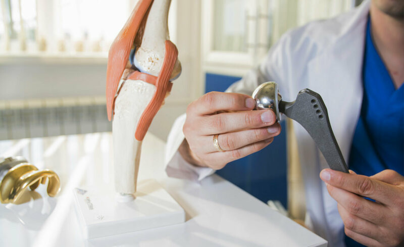 Doctor looking at joint replacement displays for knee and hip