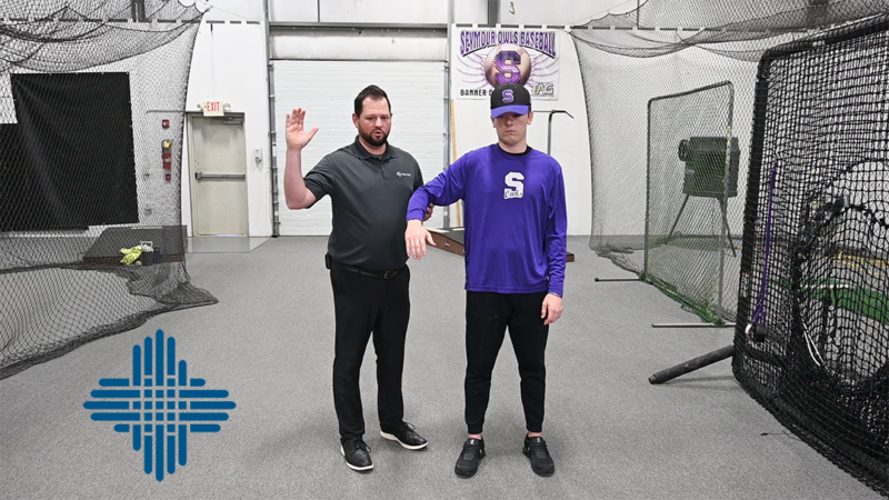 A doctor demonstrating correct posture to a baseball player