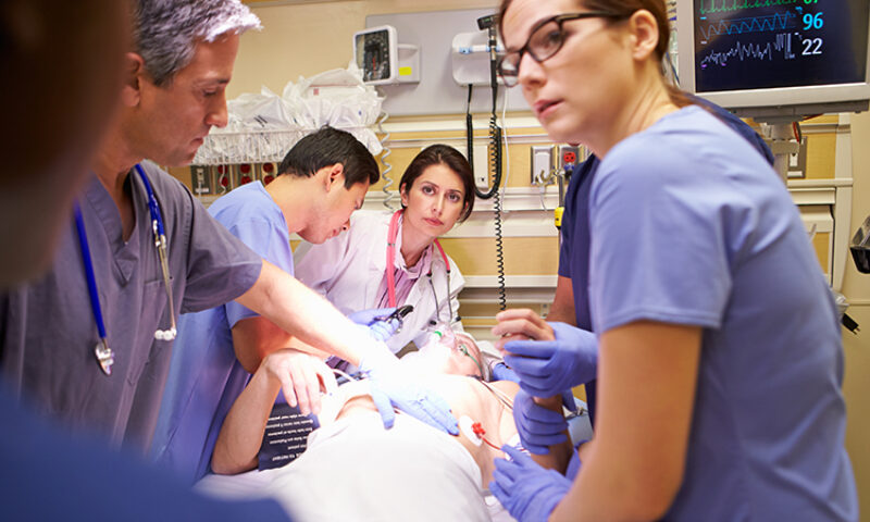 photo of concerned healthcare workers crowded around patient in the emergency room