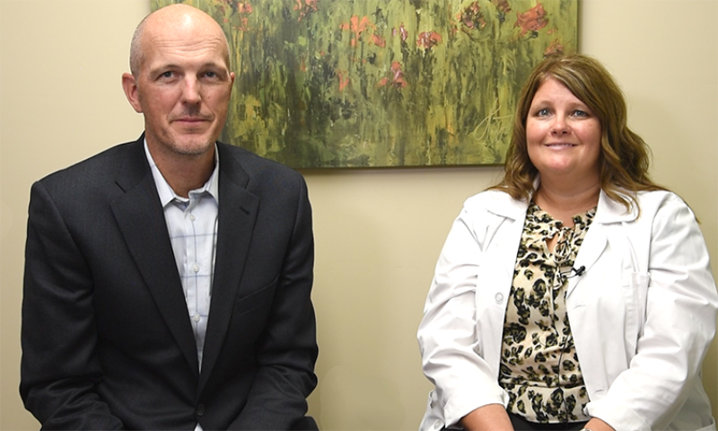 Man and woman sitting in front of painting