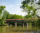 A covered bridge of Jackson County IN stands proudly over a lazy river. Green trees stretch out over the water.