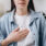 Woman hold her hand to the center of her chest to signal acid reflux pain