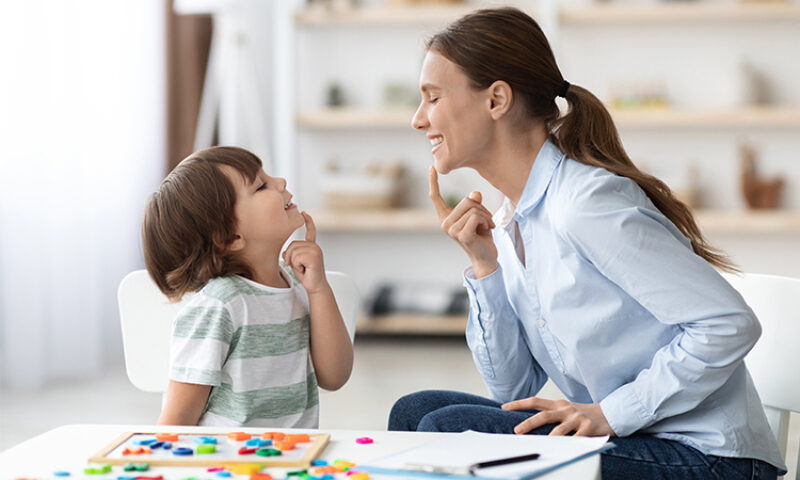 woman working with young boy both pointing at their chins