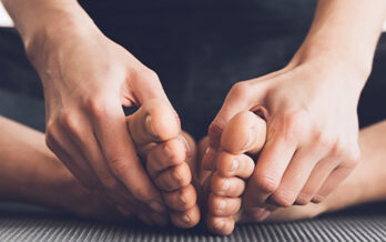 Close up of person holding their bare feet sat in a yoga pose
