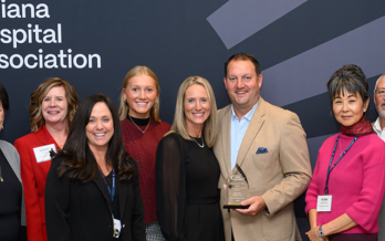 image of individuals from Schneck Medical Center and Indiana Hospital Association surround Dr. Eric Fish and his family