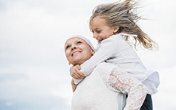 Lady with covering over her head holds laughing child on her back