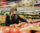 Woman wearing a mask at the grocery store as she chooses produce
