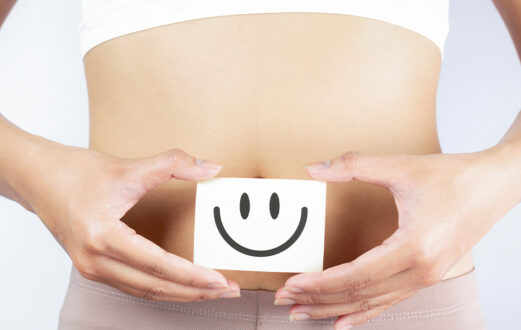 Woman holding a smiley face block in front of stomach