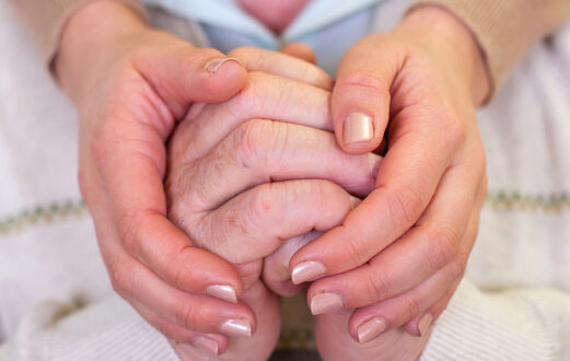 A woman holding a man's hands over his shoulders