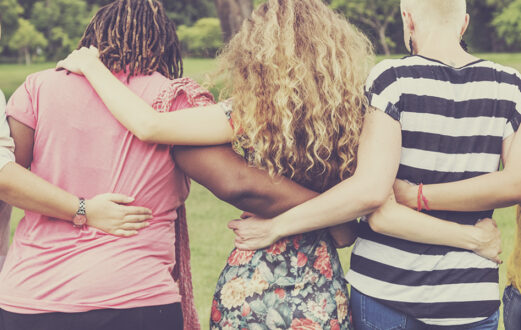 group of people pictured from behind with their arms around each other's waist