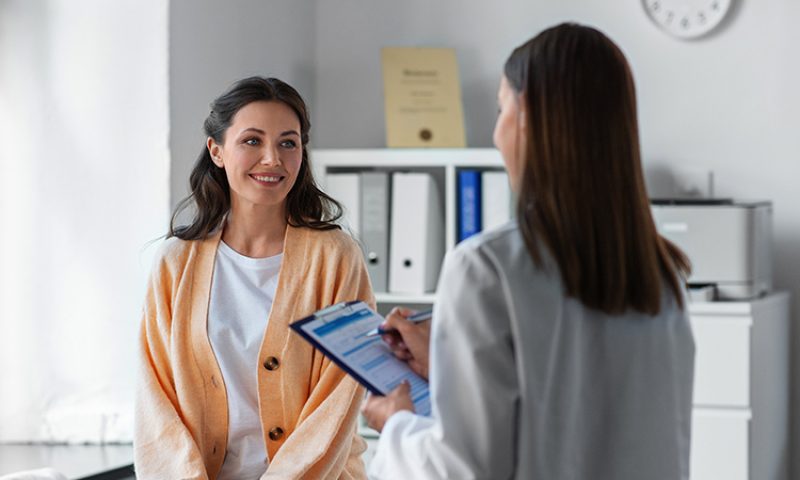 photo of a woman in a hospital room while a staff member writes down information
