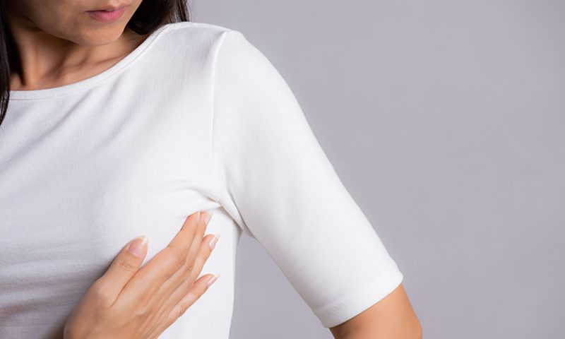 woman pressing chest for self exam